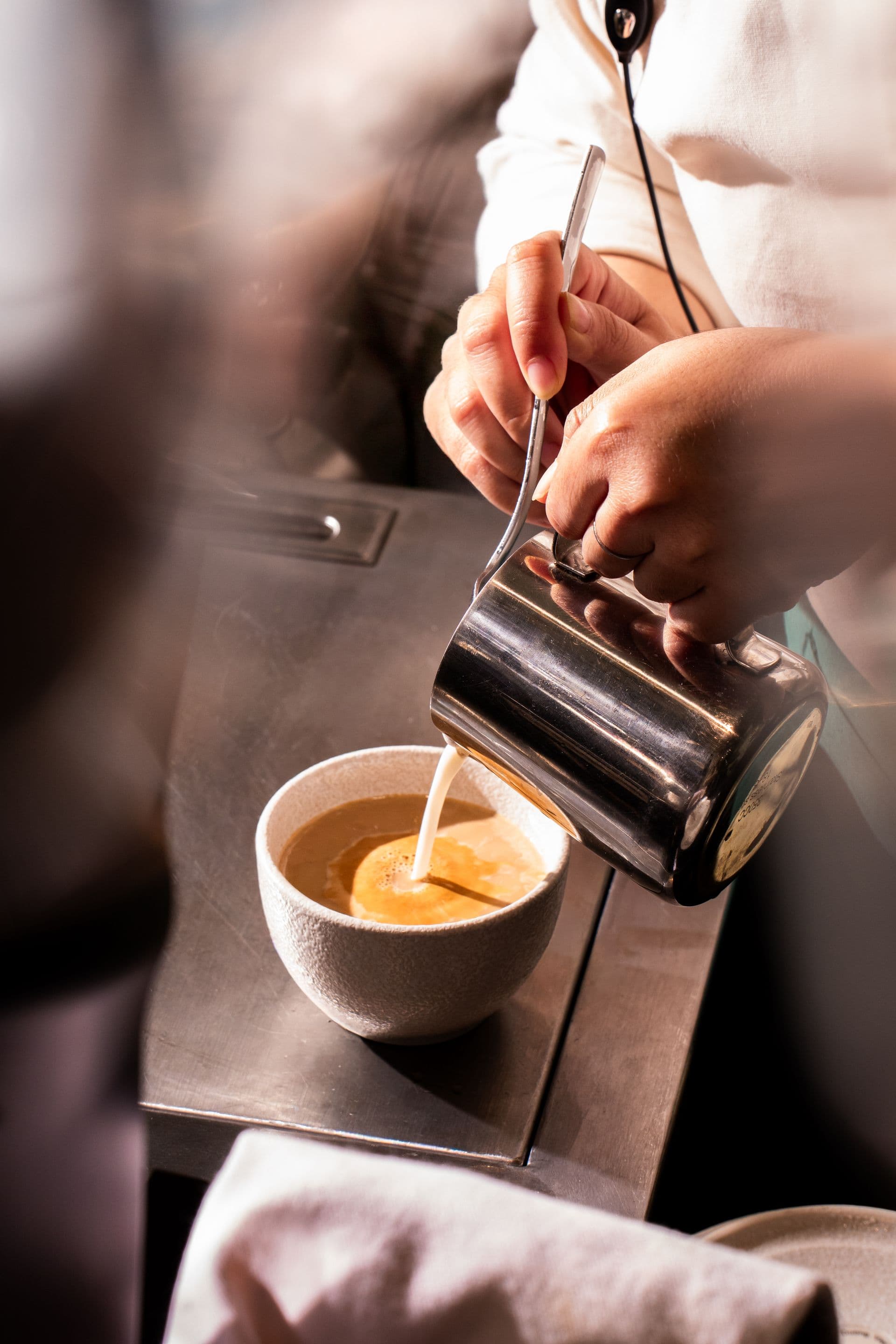 Barista pouring milk into coffee